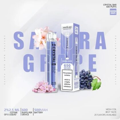 Image promotionnelle pour la vape jetable Crystal Bar au goût de raisin Sakura, présentant l'appareil à vaper, l'emballage et les graphismes de raisins et de fleurs de cerisier, avec du texte mettant en évidence des fonctionnalités telles que 600 bouffées, de la nicotine 2% et une batterie de 500 mAh.