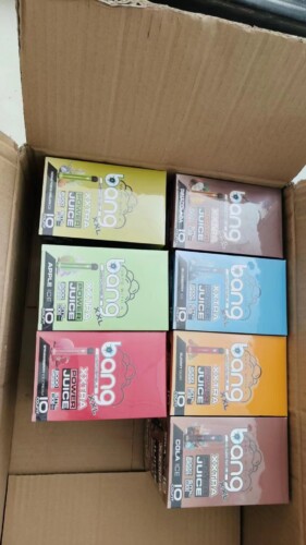 Een kartonnen doos met verschillende smaken Bang XXL wegwerp-vapes, netjes gerangschikt, waaronder Apple Ice, Strawberry Ice Cream, Gummy Bear, Cola Ice en nog veel meer.